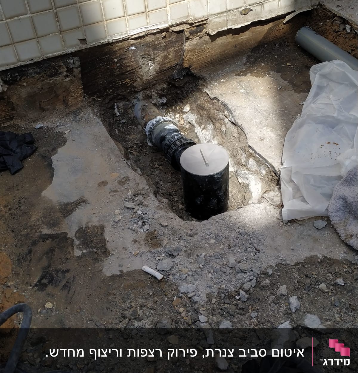 צינור שחור עם מכסה לבן בתוך חפירה ברצפה